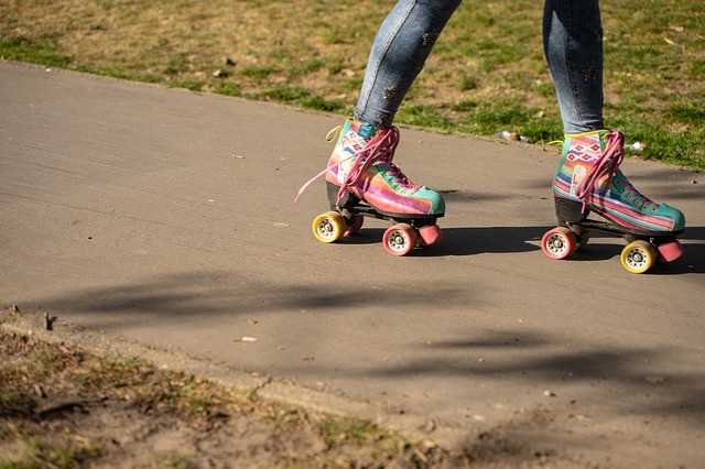 Ankle down shot of girl skating on sidewalk with colorful roller skates