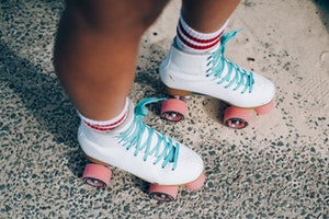 Photo of person wearing white roller skates with pink wheels
