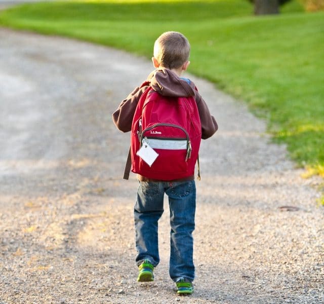 Small child with red backpack walking to school