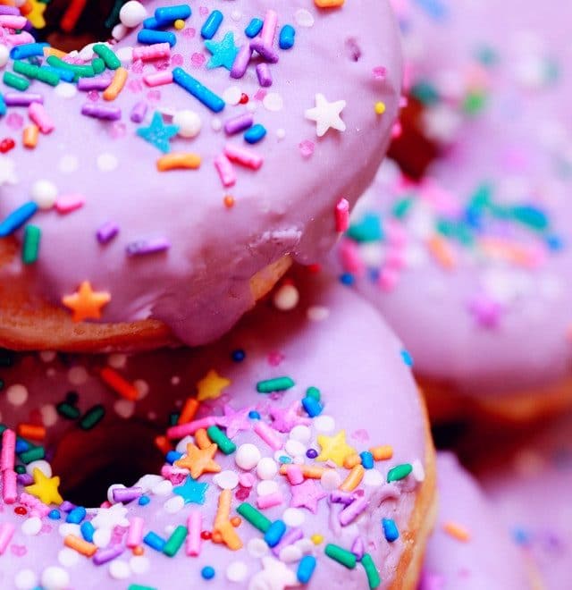 Stack of pink birthday donuts with colorful sprinkles